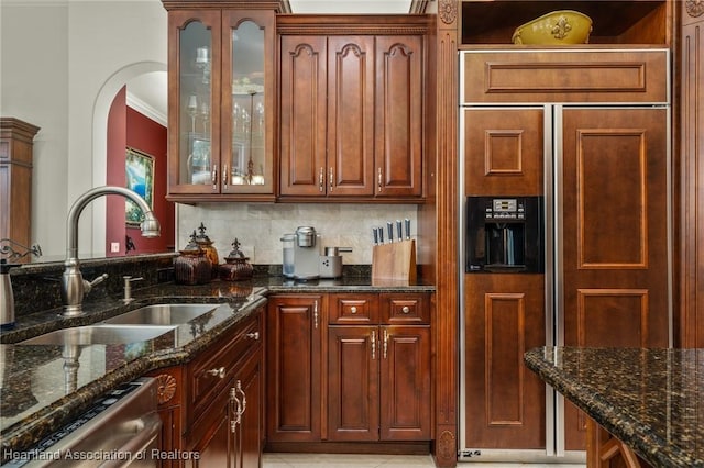 kitchen with dishwasher, dark stone countertops, paneled refrigerator, and sink