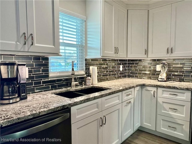 kitchen with white cabinetry, sink, light stone countertops, and dishwasher