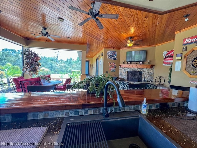 kitchen featuring a stone fireplace and wood ceiling