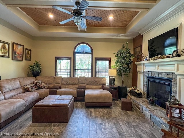 living room with a stone fireplace, hardwood / wood-style flooring, ceiling fan, a tray ceiling, and wood ceiling