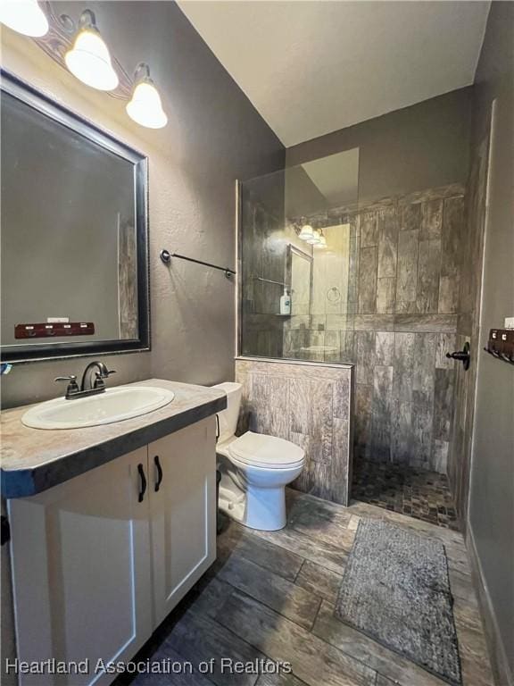 bathroom with tiled shower, vanity, and toilet