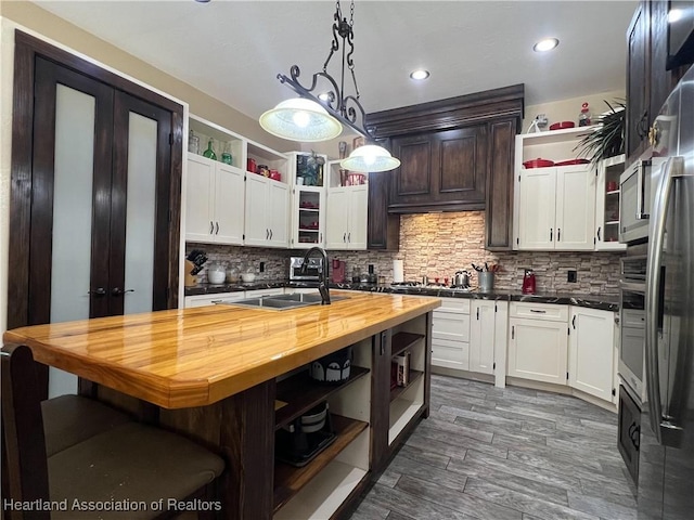 kitchen with decorative backsplash, sink, wooden counters, and decorative light fixtures