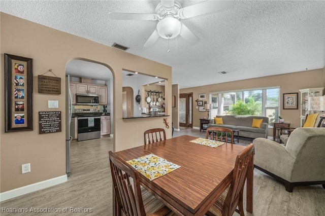 dining room featuring a textured ceiling, light hardwood / wood-style floors, and ceiling fan