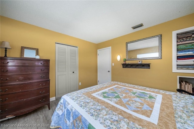 bedroom featuring wood-type flooring, a textured ceiling, and a closet