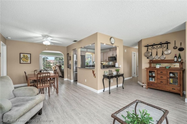 living room with ceiling fan, light hardwood / wood-style floors, and a textured ceiling