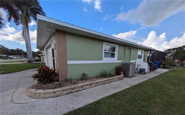 view of property exterior with a yard, central AC unit, and a garage