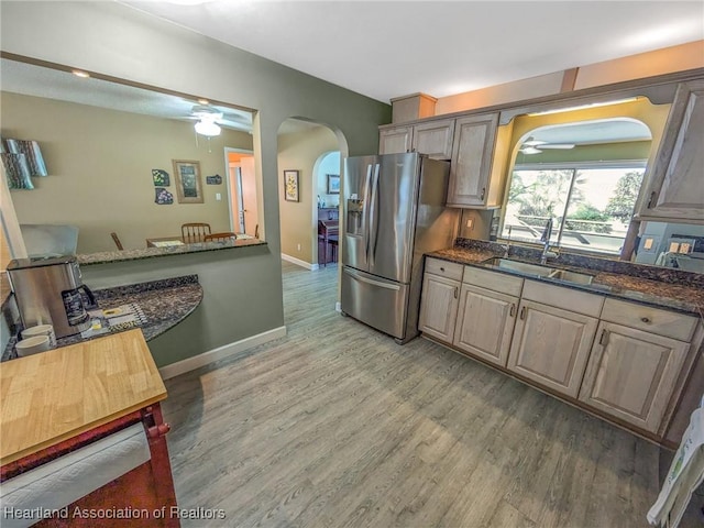 kitchen featuring stainless steel fridge, hardwood / wood-style flooring, dark stone counters, and sink