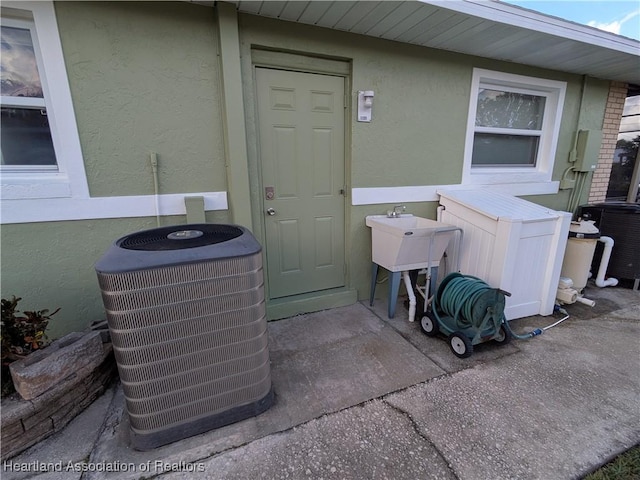 view of exterior entry featuring central air condition unit