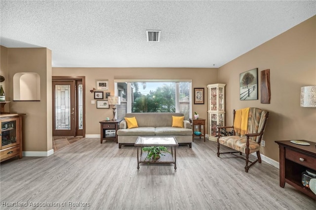 living room featuring light hardwood / wood-style flooring and a textured ceiling