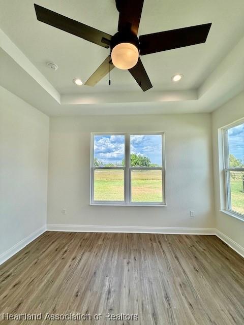 5279 Pebble Dr, Sebring, FL 33872 - empty room with baseboards, ceiling fan, wood finished floors, and a tray ceiling