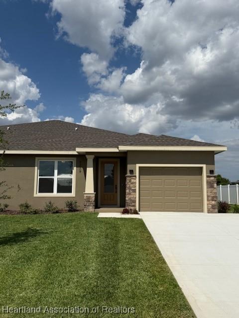 5279 Pebble Dr, Sebring, FL 33872 - view of front facade with a front yard, stone siding, stucco siding, an attached garage, and driveway