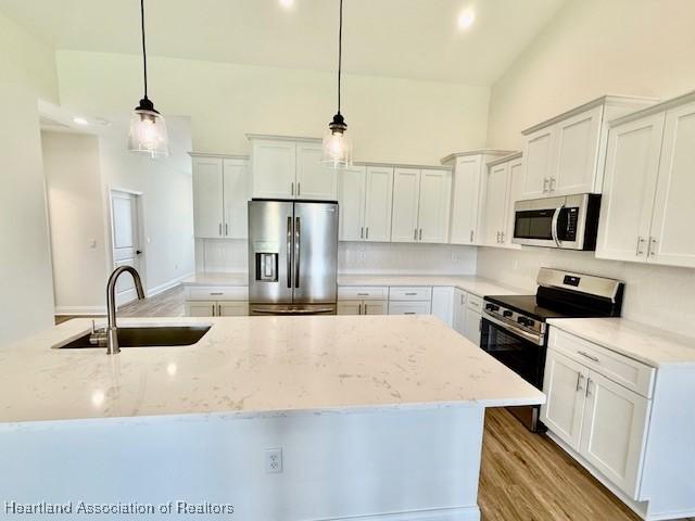 5279 Pebble Dr, Sebring, FL 33872 - kitchen with a sink, white cabinetry, appliances with stainless steel finishes, and a center island with sink