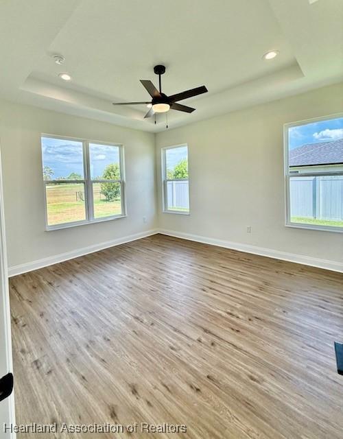 5279 Pebble Dr, Sebring, FL 33872 - spare room featuring a raised ceiling, baseboards, a ceiling fan, and wood finished floors