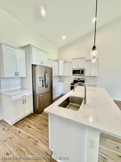 5279 Pebble Dr, Sebring, FL 33872 - kitchen with pendant lighting, light wood-style floors, high vaulted ceiling, a sink, and stainless steel appliances