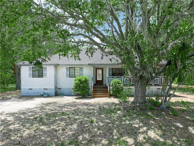 view of front facade featuring covered porch, a shingled roof, and crawl space