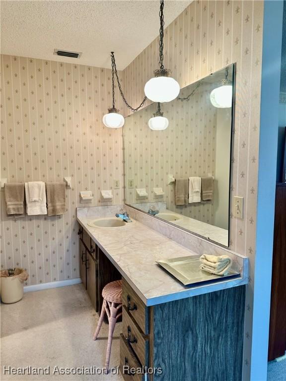 1704 Palm St, Sebring, FL 33870 - bathroom featuring wallpapered walls, a textured ceiling, baseboards, and vanity