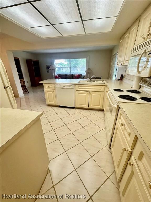1704 Palm St, Sebring, FL 33870 - kitchen with white appliances, light tile patterned flooring, light countertops, open floor plan, and a sink