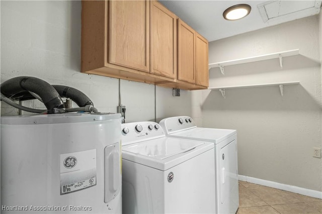 washroom with washing machine and dryer, electric water heater, light tile patterned floors, and cabinets