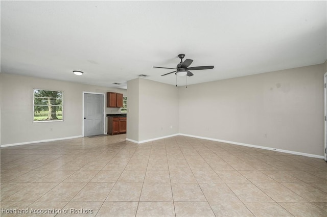 empty room with ceiling fan and light tile patterned floors