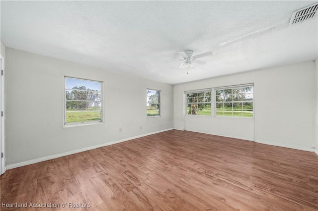 empty room featuring hardwood / wood-style flooring, ceiling fan, and a textured ceiling