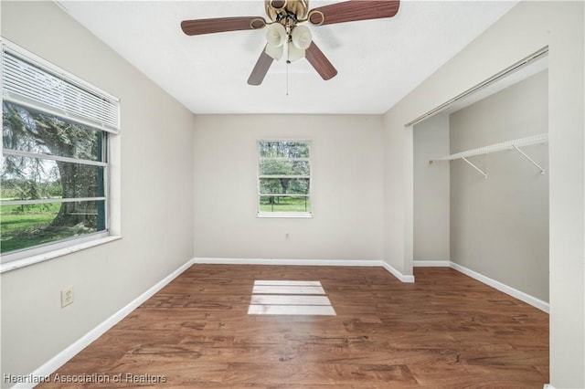 unfurnished bedroom featuring dark hardwood / wood-style flooring, ceiling fan, a closet, and multiple windows