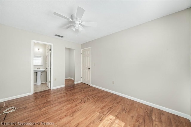 unfurnished bedroom with ensuite bath, ceiling fan, sink, and hardwood / wood-style flooring