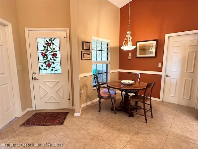 dining room with light tile patterned floors, baseboards, and a towering ceiling