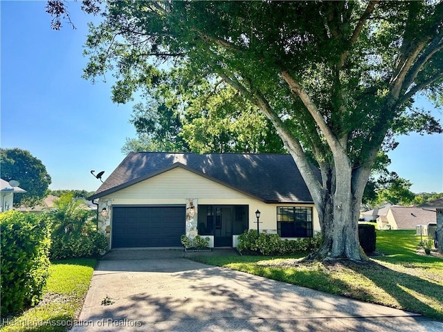 ranch-style house featuring a front lawn, stone siding, concrete driveway, an attached garage, and a shingled roof