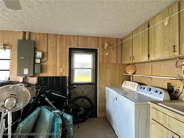 laundry area with electric panel, plenty of natural light, wood walls, and washing machine and clothes dryer