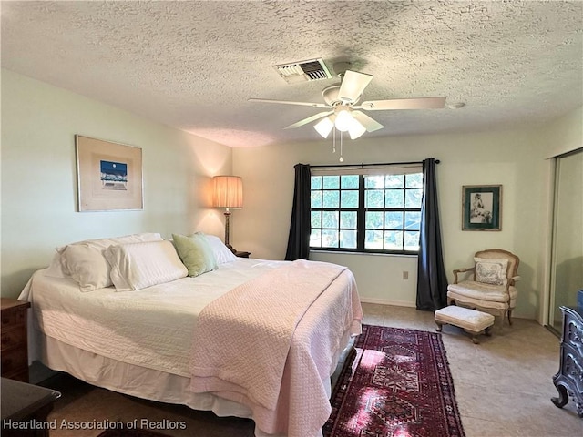 bedroom featuring visible vents, a textured ceiling, a closet, and a ceiling fan