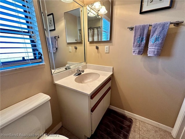 bathroom with baseboards, toilet, vanity, and tile patterned flooring