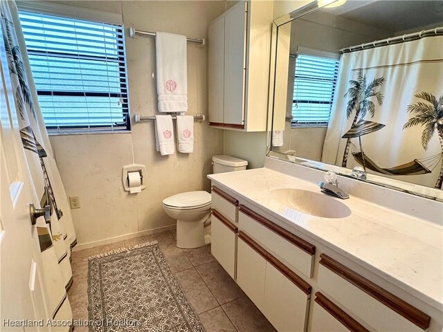 bathroom featuring tile patterned floors, toilet, curtained shower, baseboards, and vanity