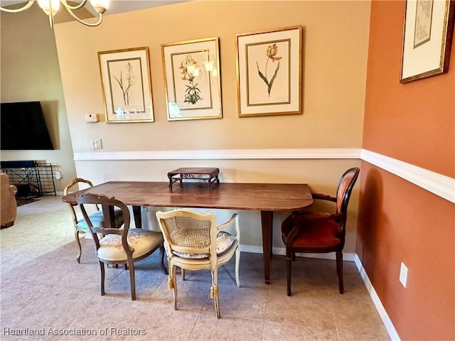 dining area with tile patterned floors, baseboards, and an inviting chandelier