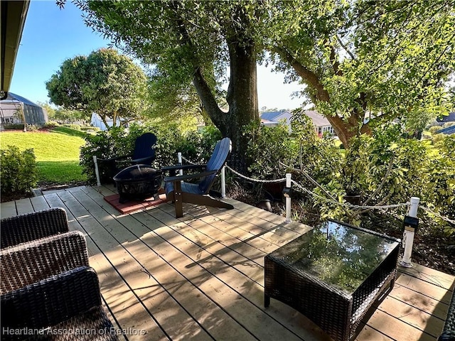 wooden terrace featuring a fire pit and a lawn