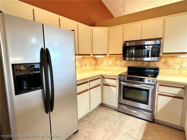 kitchen with light tile patterned floors, decorative backsplash, appliances with stainless steel finishes, and light countertops