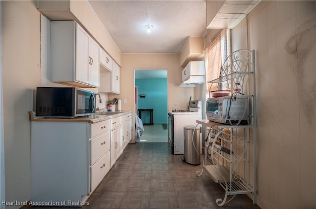 kitchen with white cabinets, range, and stainless steel microwave