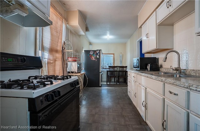 kitchen featuring freestanding refrigerator, gas range, under cabinet range hood, a sink, and black microwave