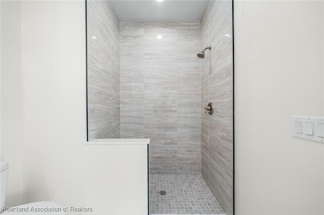 bathroom with tiled shower and toilet