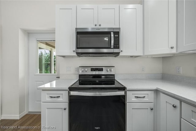 kitchen featuring white cabinets, light stone counters, wood-type flooring, and appliances with stainless steel finishes