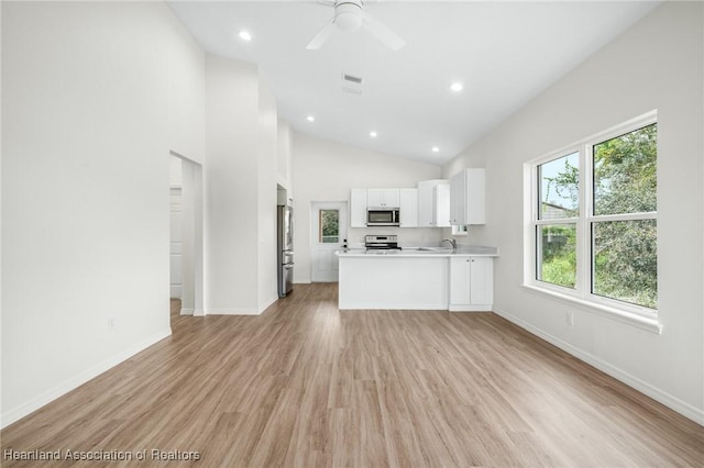 kitchen featuring white cabinets, appliances with stainless steel finishes, high vaulted ceiling, and a healthy amount of sunlight