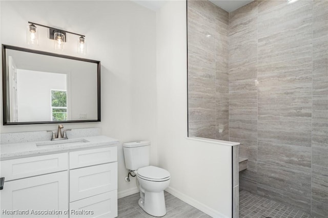 bathroom with vanity, toilet, and a tile shower