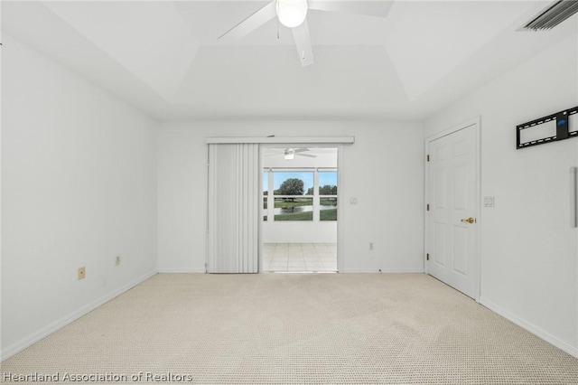 unfurnished room featuring light carpet, a tray ceiling, and ceiling fan