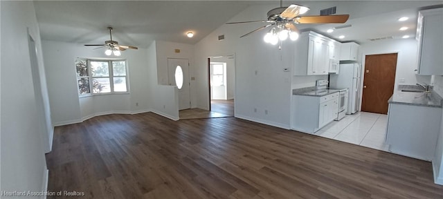 kitchen with hardwood / wood-style floors, white appliances, sink, vaulted ceiling, and white cabinetry