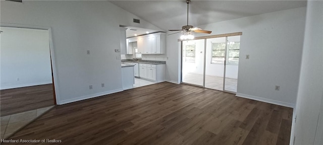 unfurnished living room with dark hardwood / wood-style floors, ceiling fan, and vaulted ceiling