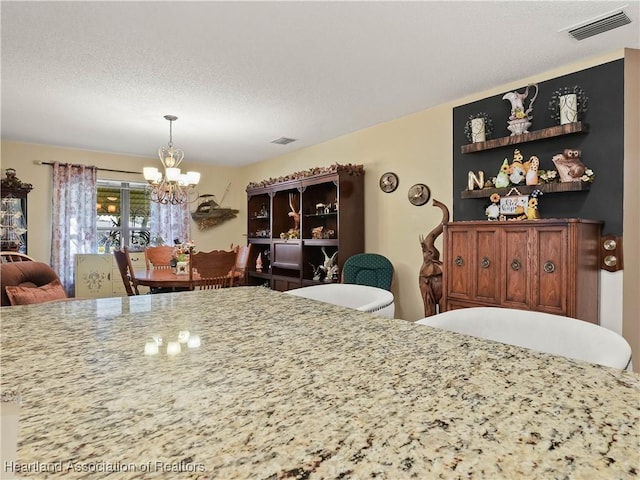 dining room with an inviting chandelier, visible vents, and a textured ceiling