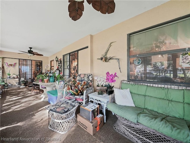 carpeted living area with a ceiling fan