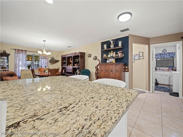 kitchen with visible vents, hanging light fixtures, an inviting chandelier, a textured ceiling, and light tile patterned flooring