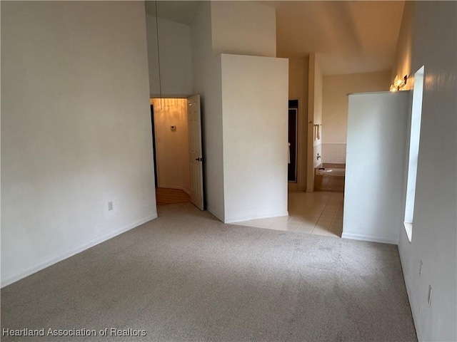 carpeted spare room featuring tile patterned flooring and a towering ceiling