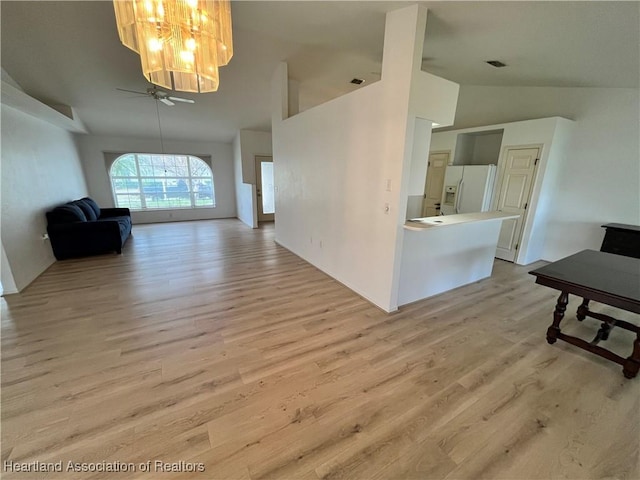 interior space featuring light wood-style flooring, ceiling fan with notable chandelier, and high vaulted ceiling