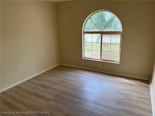 spare room with baseboards and wood finished floors